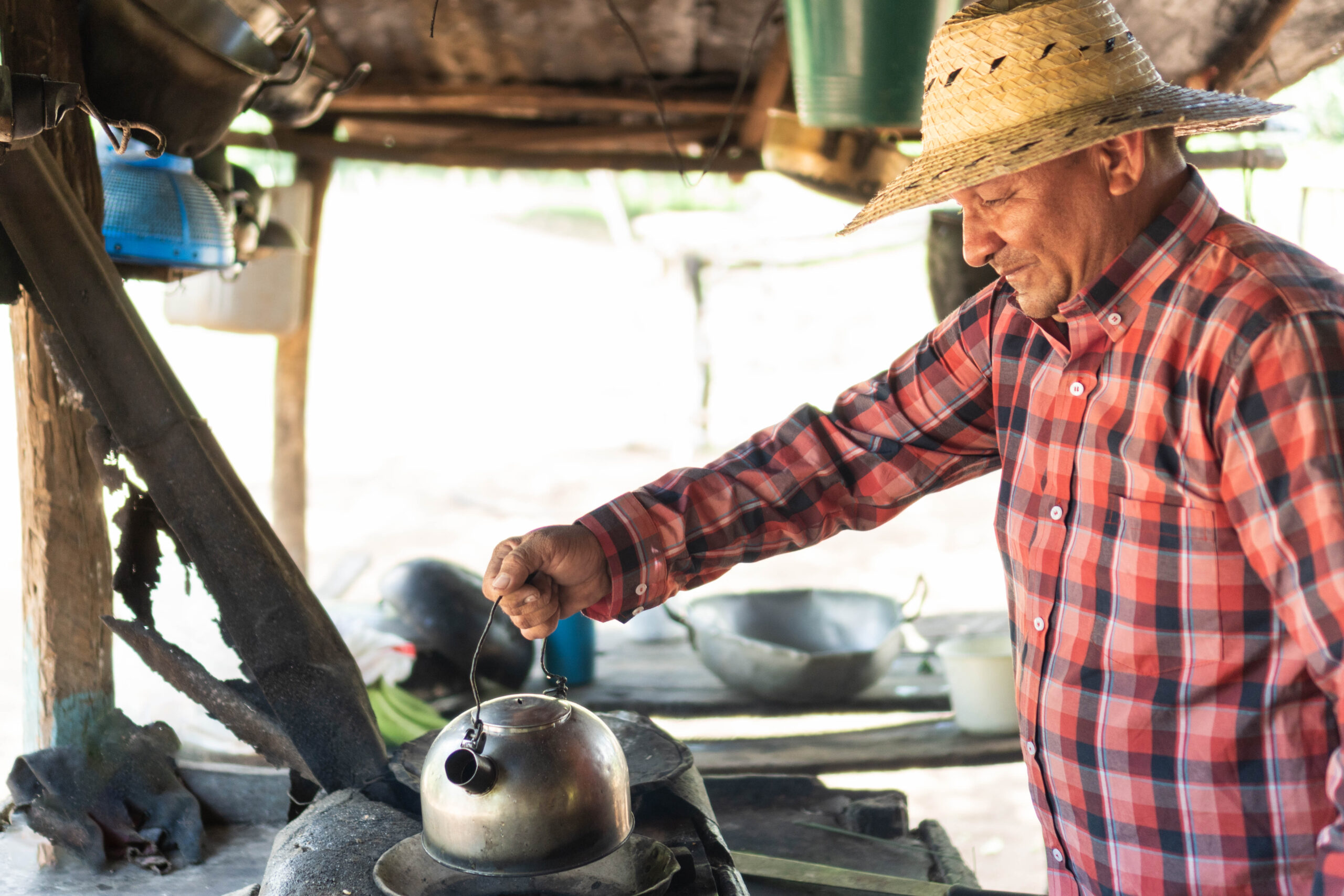 A man preparing coffee in a traditional kitchen with a rustic stove.
