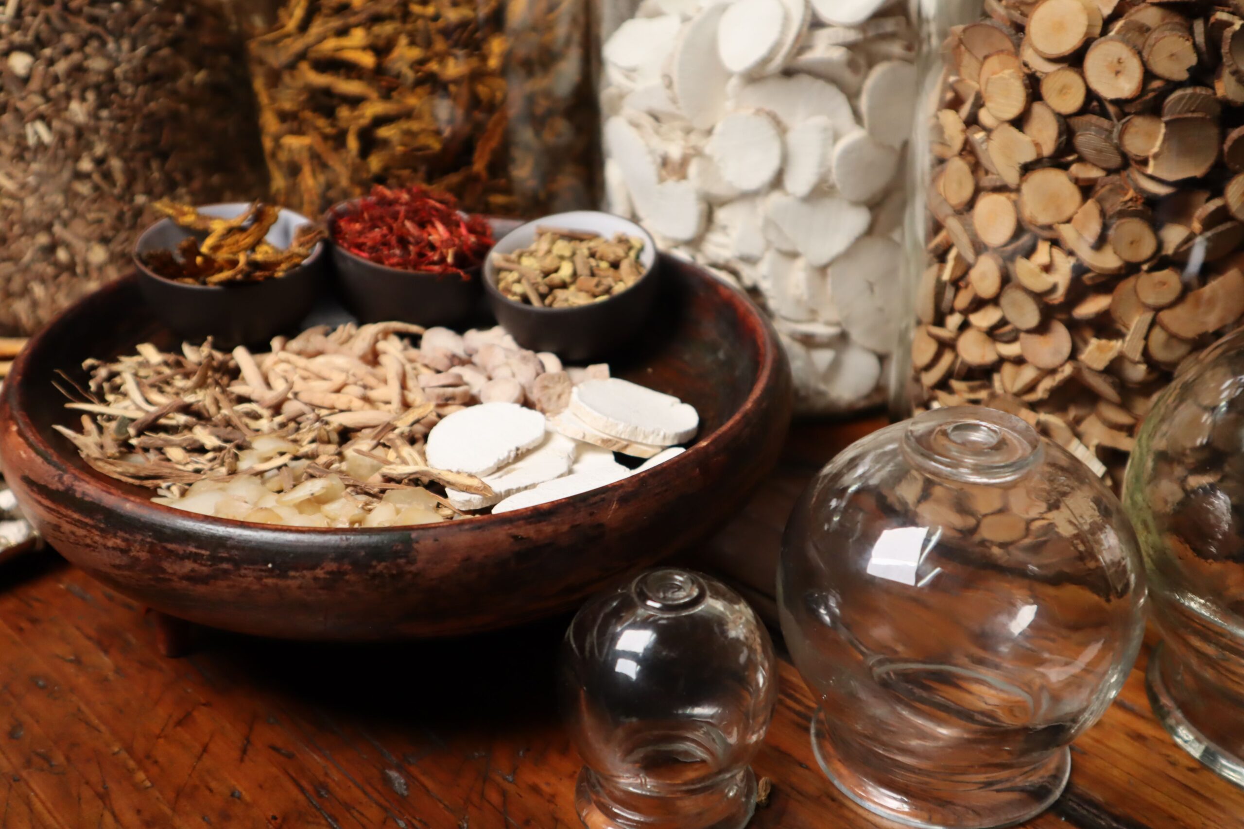Close-up of herbal ingredients and glass jars used in traditional Chinese medicine therapy.